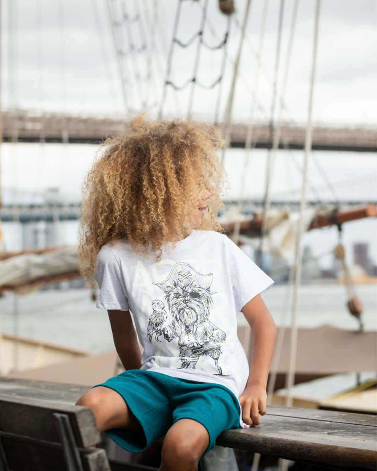 Adventurous boy wearing Captain York Graphic Tee on a boat, perfect for back to school style. Playful, high-quality kids clothes!
