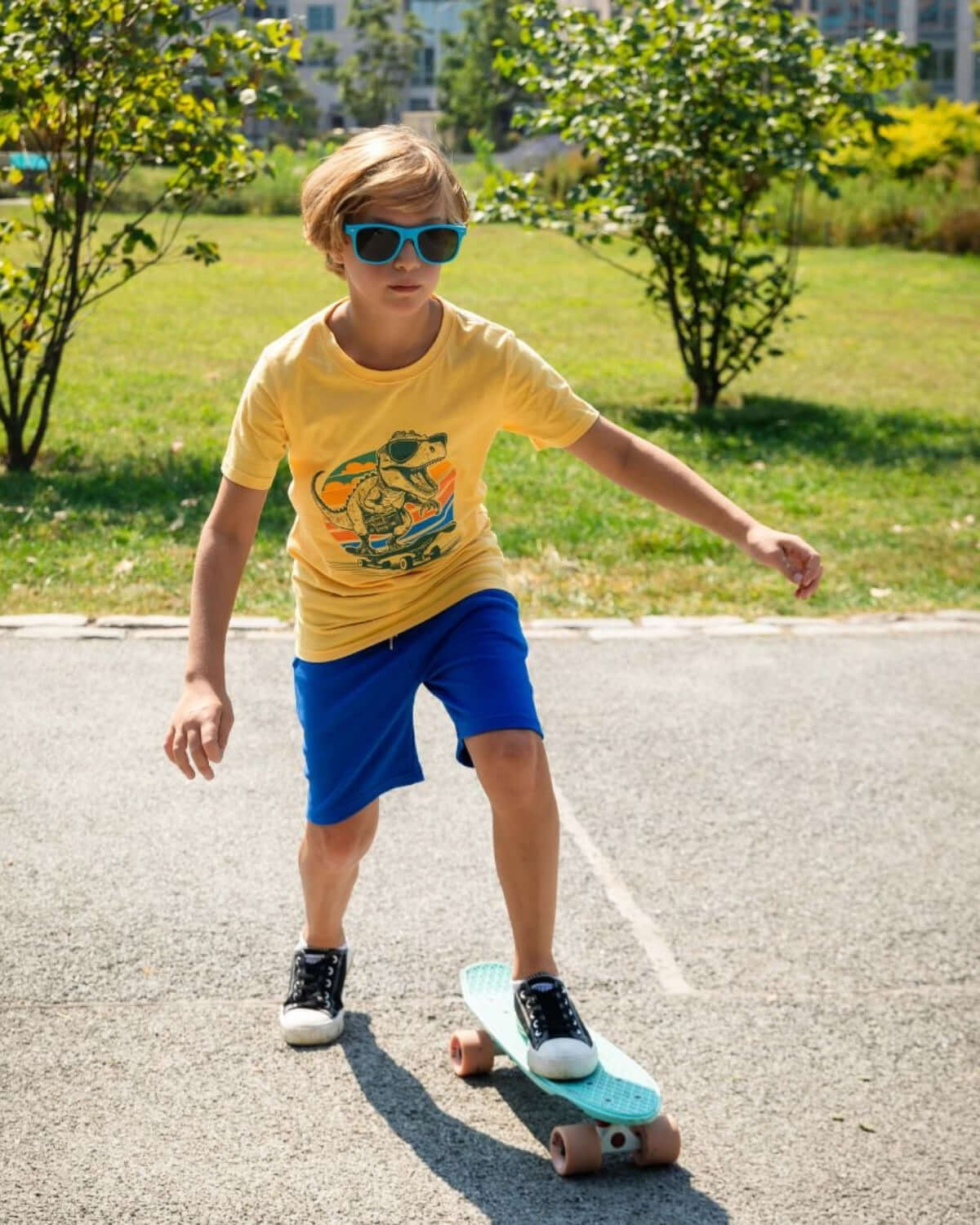 Cool kid skating in a Dino Rock graphic tee and shades, embodying fun in stylish kids clothes for adventurous play! 💚