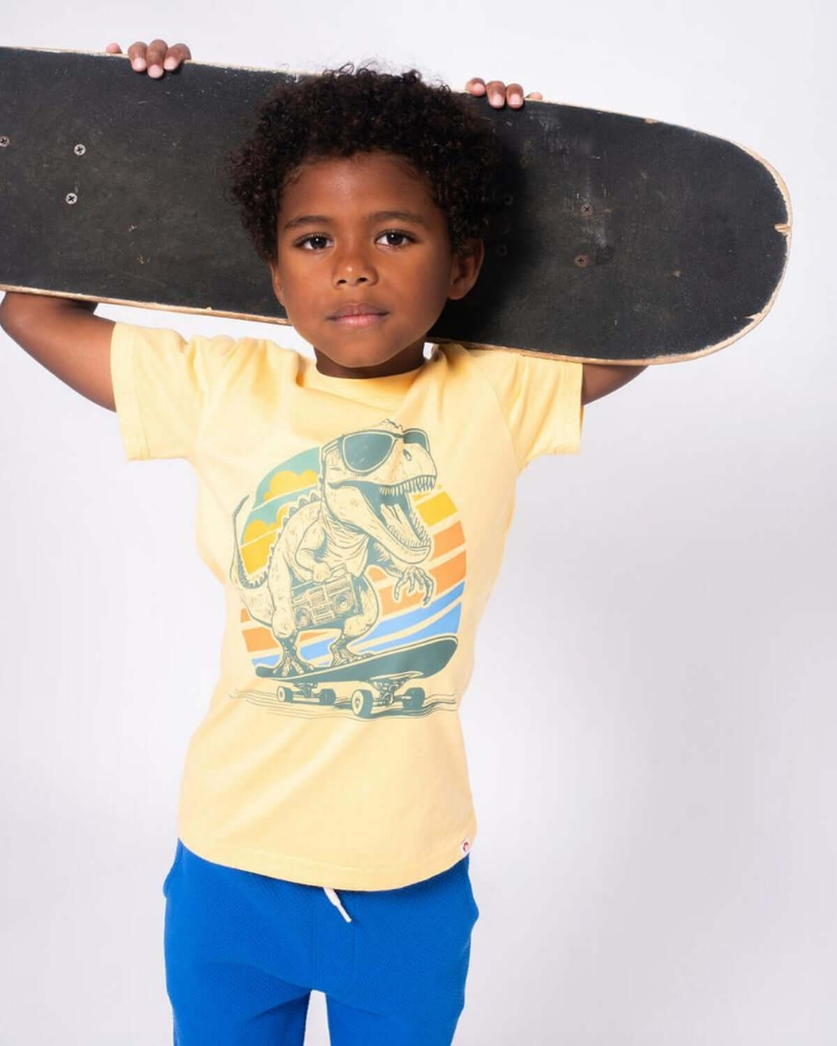 Stylish boy rocking a Dino Rock Graphic Tee and skateboard, ready for dino-mite adventures and back-to-school fun!
