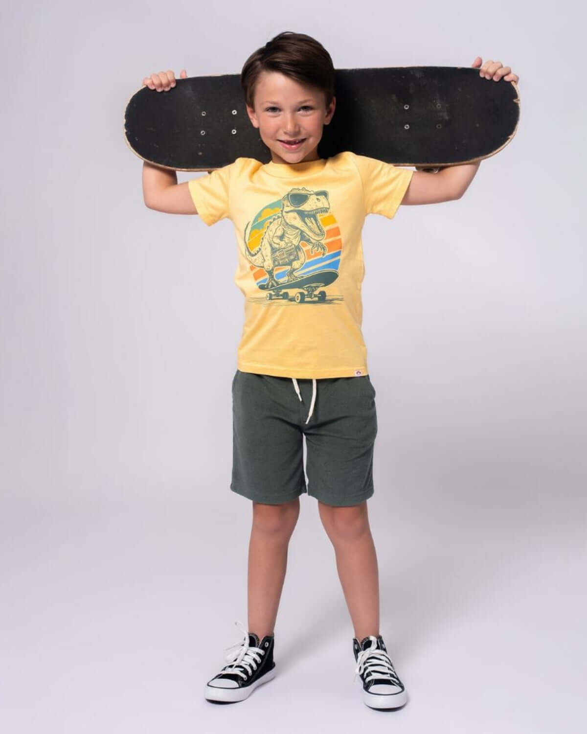 Stylish boy rocking a Dino Rock Graphic Tee and shorts, ready for skate adventures in high-quality kids clothes!