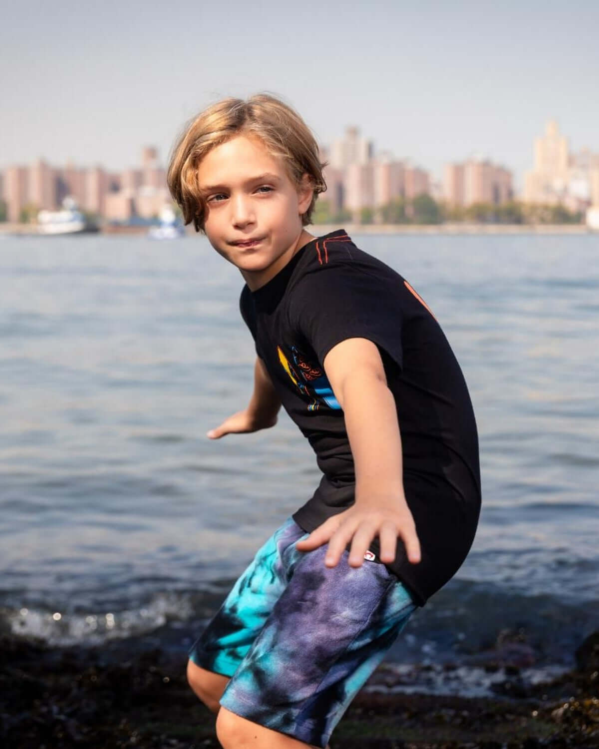 Kid showcasing the hang loose style in a fun graphic tee by the water, ready for surf adventures!