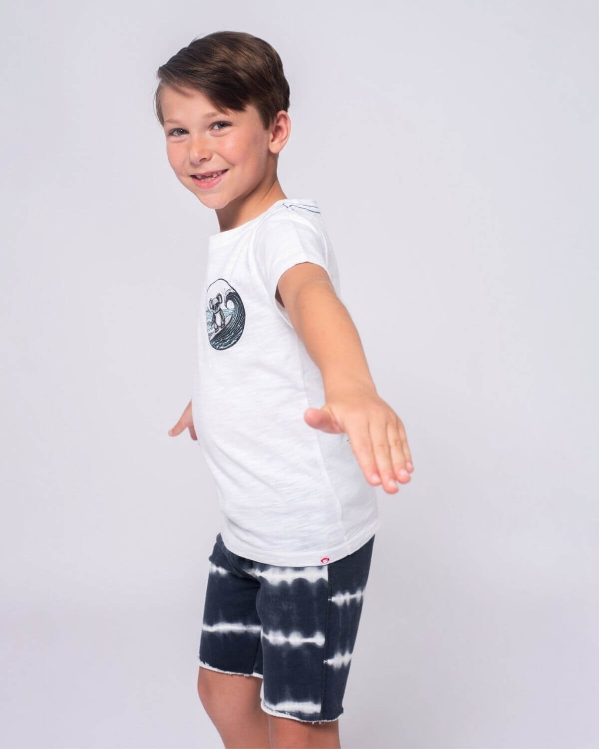 Stylish boy in a Koala Surf Graphic Tee, ready for beach fun in high-quality kids clothes. Perfect for back-to-school adventures!