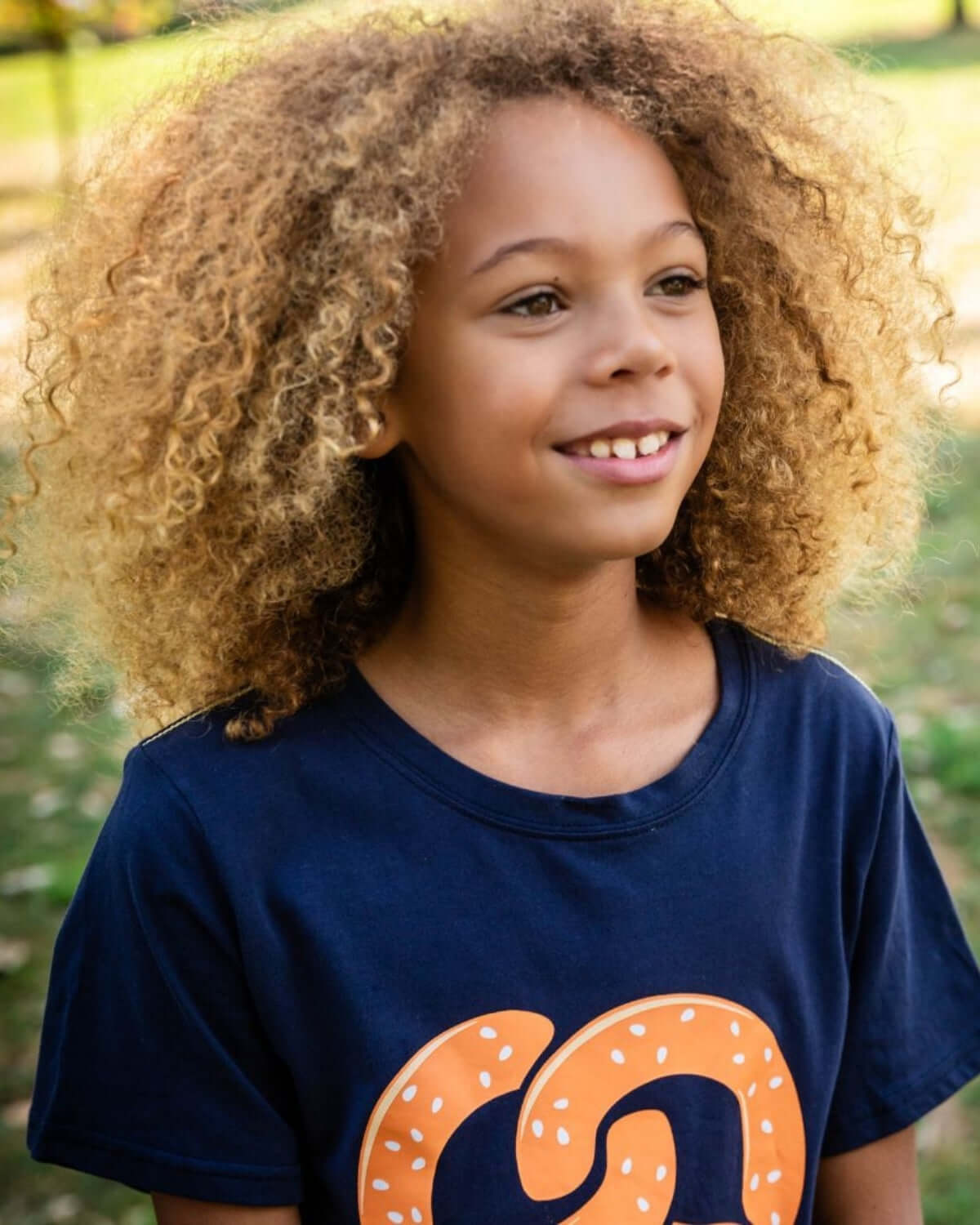 Happy kid modeling a navy pretzel graphic tee, blending fun style and comfort in high-quality kids clothes.