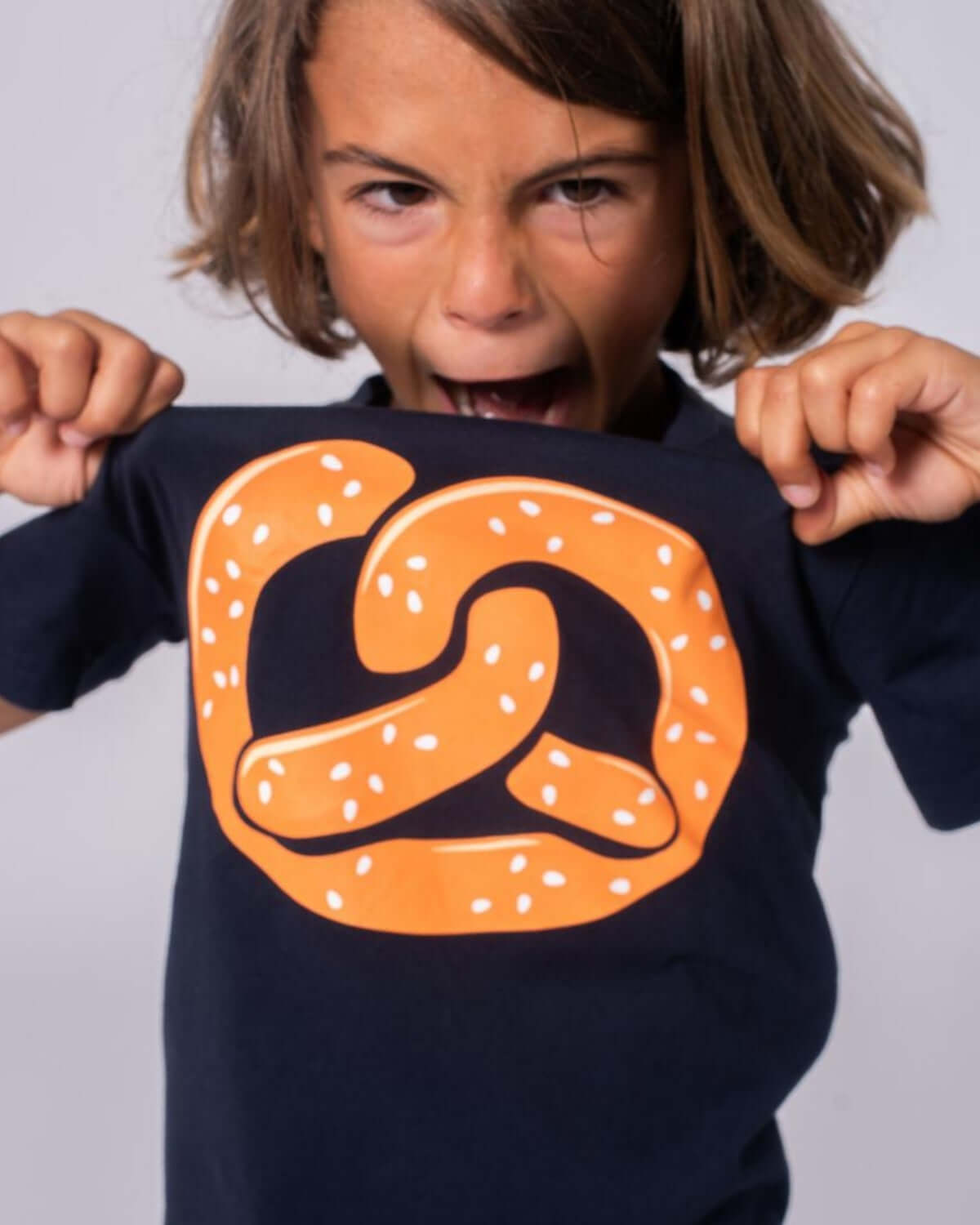 Zesty boy showing off a fun pretzel graphic on a comfy tee, ready for school or play in playful style!