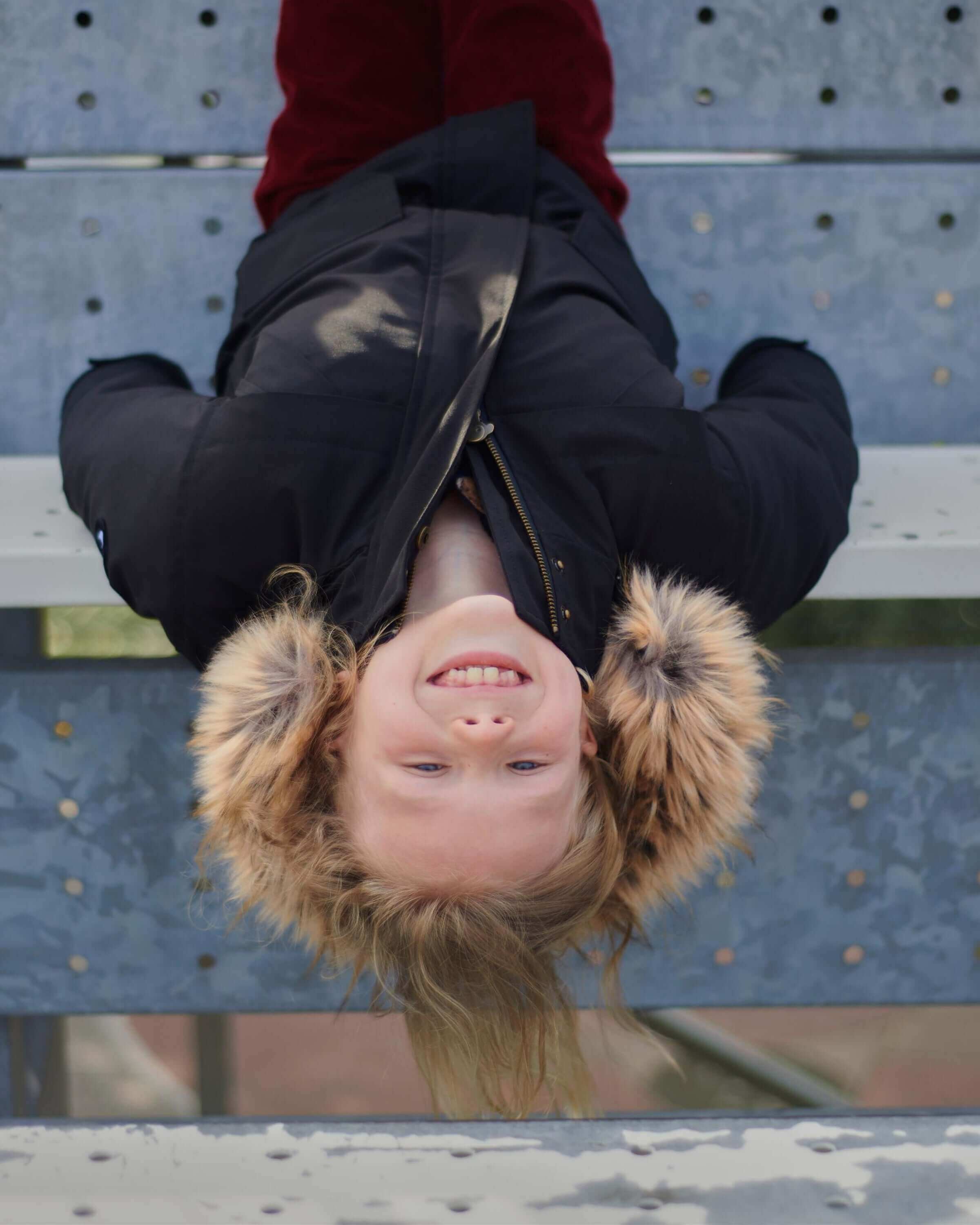 Joyful kid rocking a sleek black transit coat with faux fur hood, making winter fun and stylish! #KidsClothes #BackToSchool