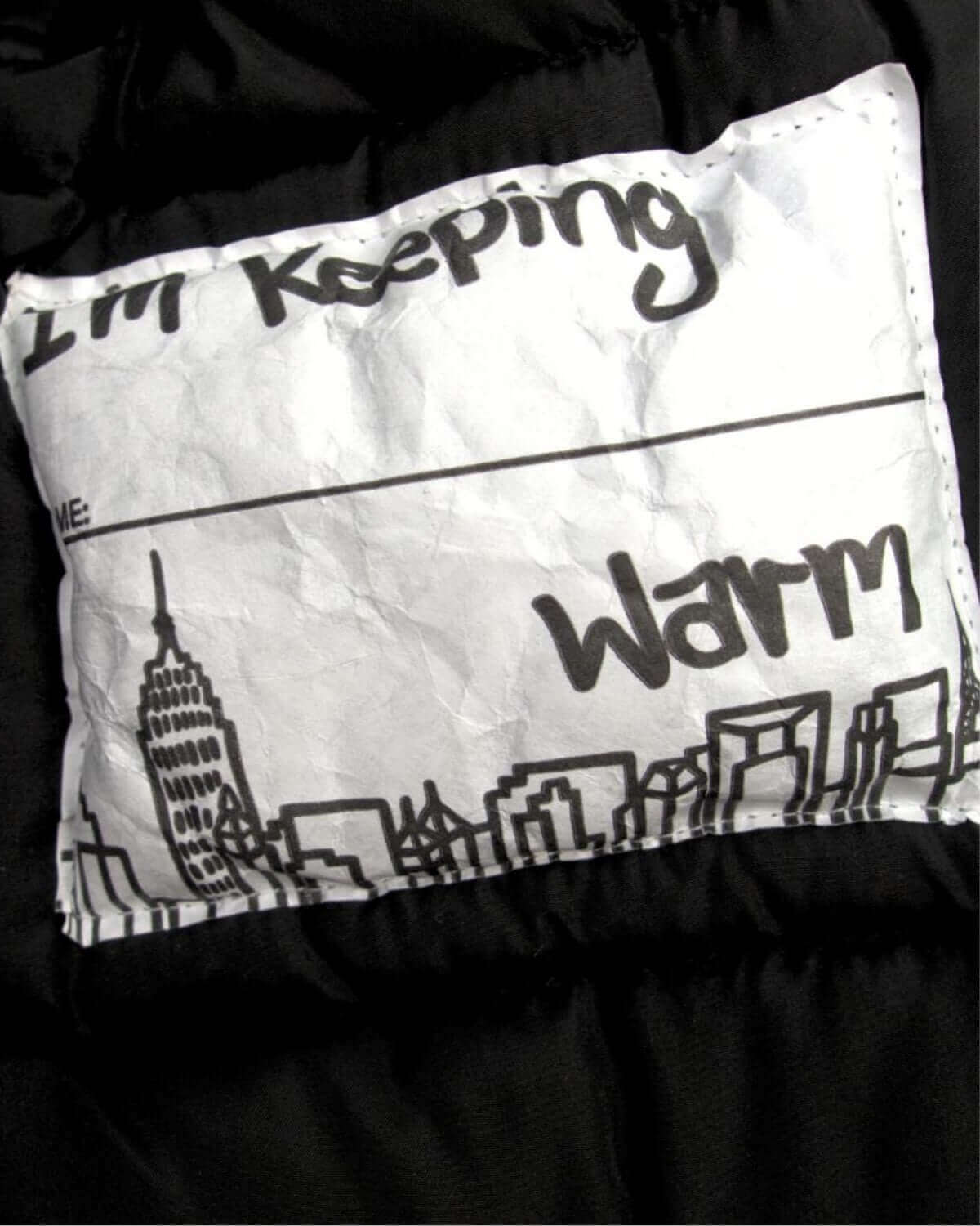 Cozy faux fur lining label with playful city skyline design, part of Appaman's sleek Black City Transit Coat for stylish warmth.