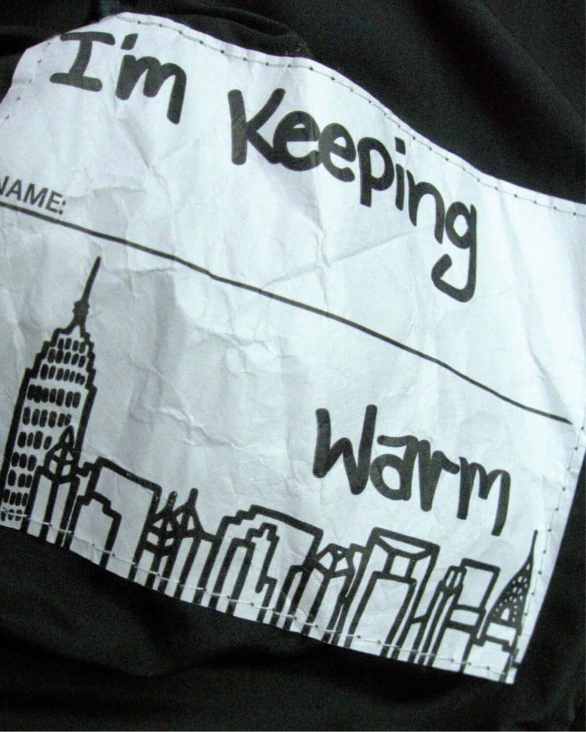 Fun inner label on the Turnstile Jacket that reads "I'm Keeping Warm" with a city skyline design, adding a playful twist!