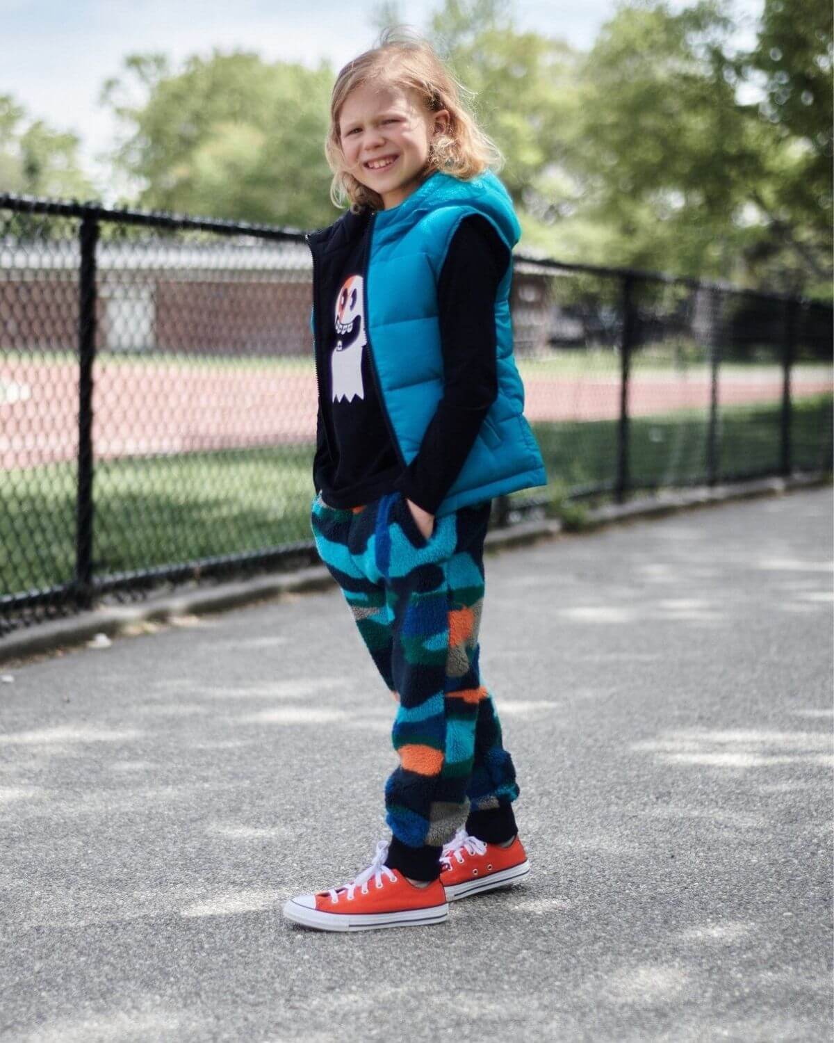 Cheerful kid in a Blue Jewel vest, stylishly rocking playful pants and sneakers, ready for back-to-school adventures!