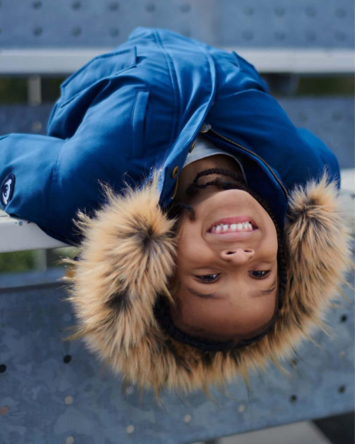Playful kid sporting a cozy blue City Transit Coat with a faux fur hood, ready to take on winter adventures in style!