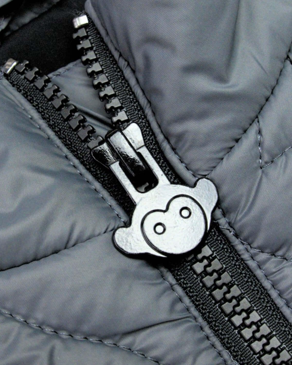 Close-up of playful monkey zipper on iron packable vest, adding a fun touch to kids' high-quality apparel.