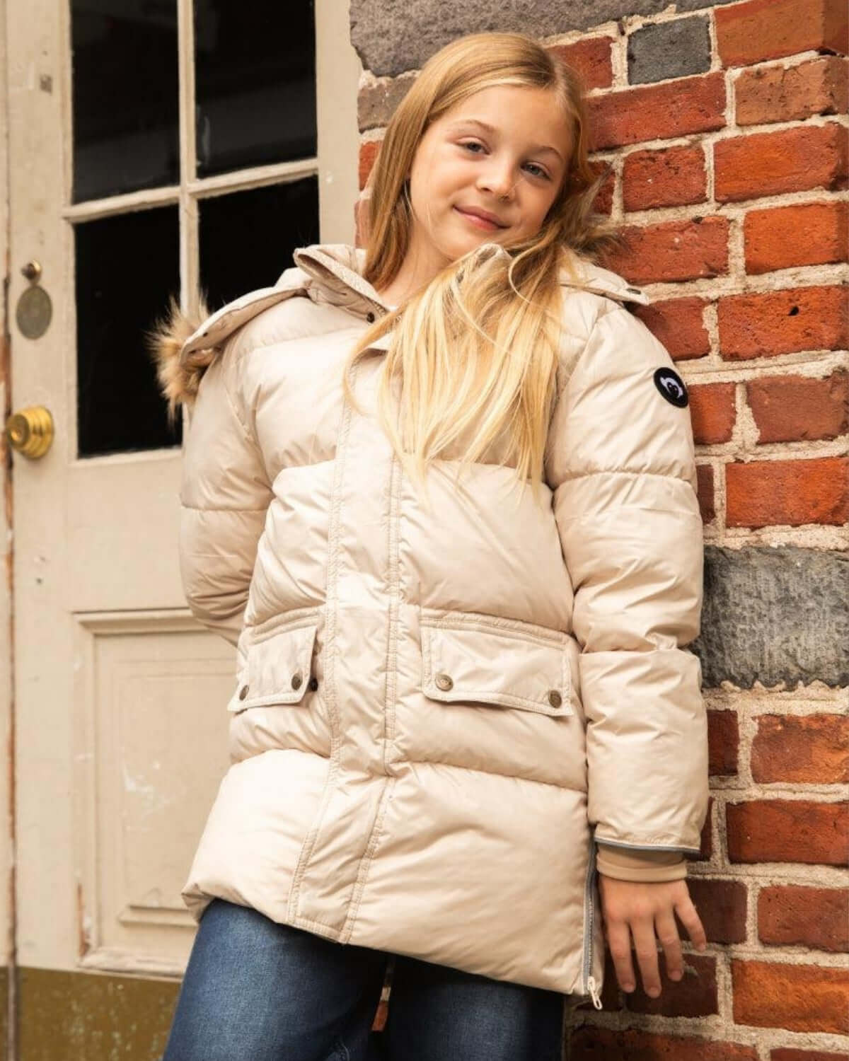 Stylish girl in ivory expedition puffer coat with faux fur hood, ready for outdoor adventures this winter!