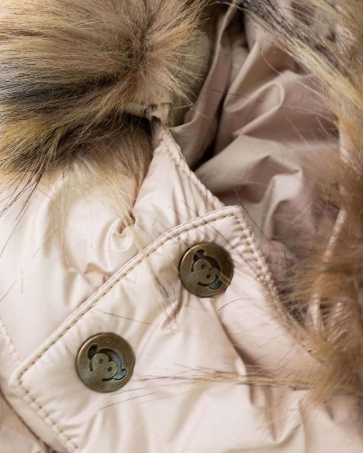 Close-up of the ivory expedition puffer coat buttons and faux fur trim, stylish and cozy for kids' winter adventures.