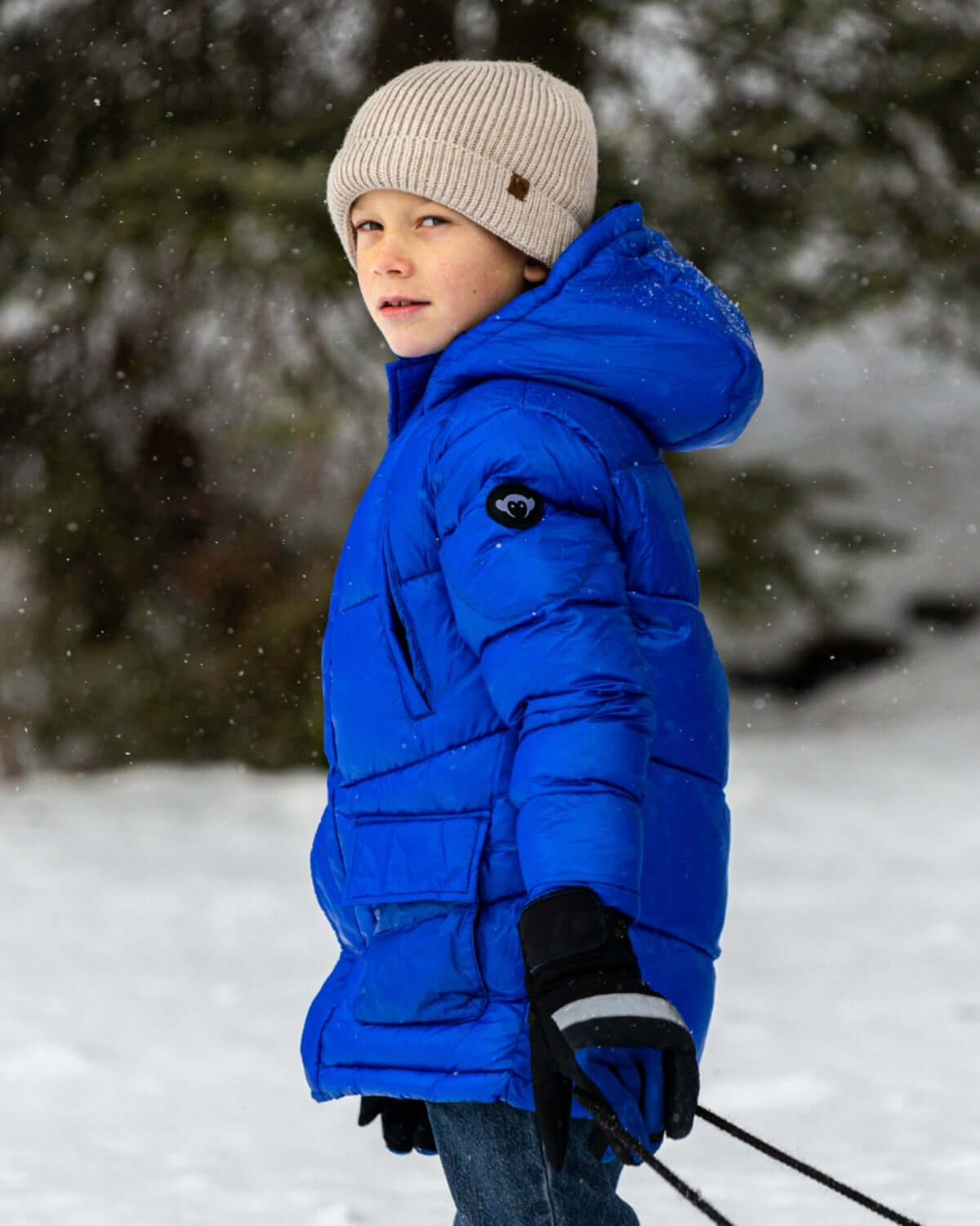 Stylish boy in Reflex Blue Summit Puffer Coat enjoying winter fun, blending warmth and playful style. Perfect winter kids clothes!