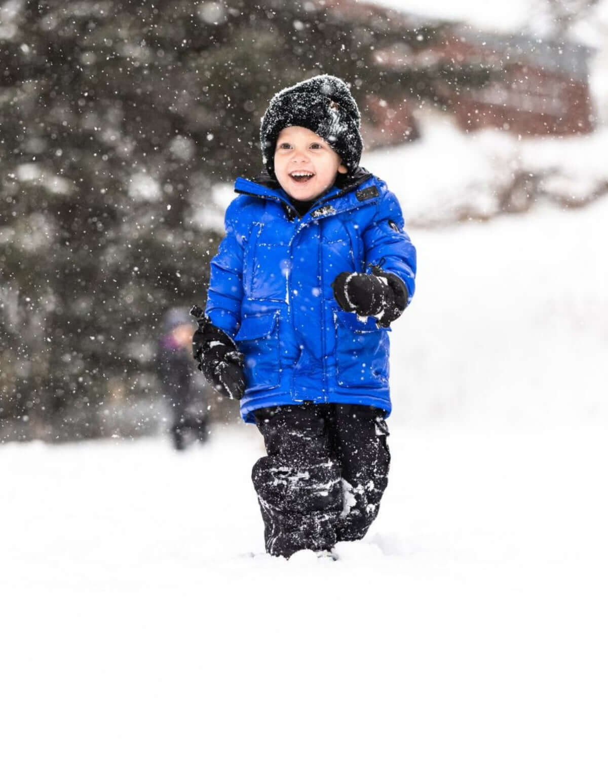 Joyful boy in a vibrant Reflex Blue Summit Puffer Coat playing in fresh snow, showcasing warmth and playful style in winter fun!