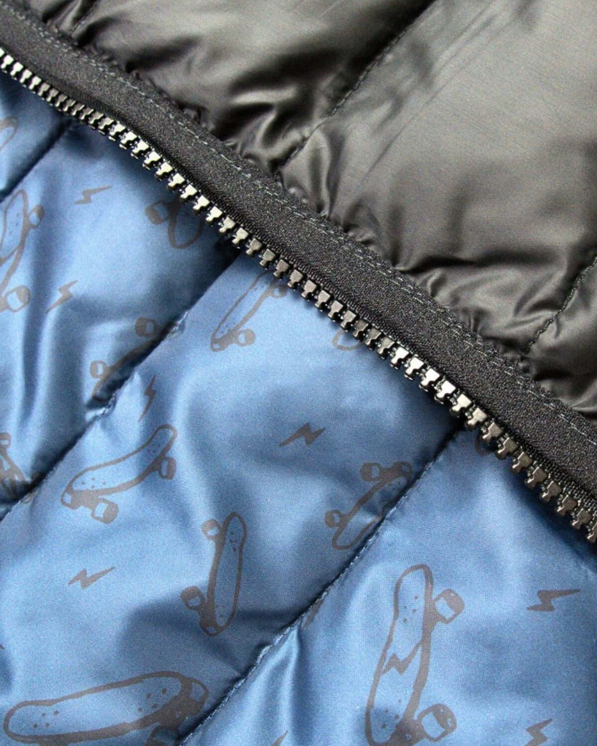 Close-up of Appaman's reversible puffer jacket showcasing blue skate print and sleek zip for stylish warmth.