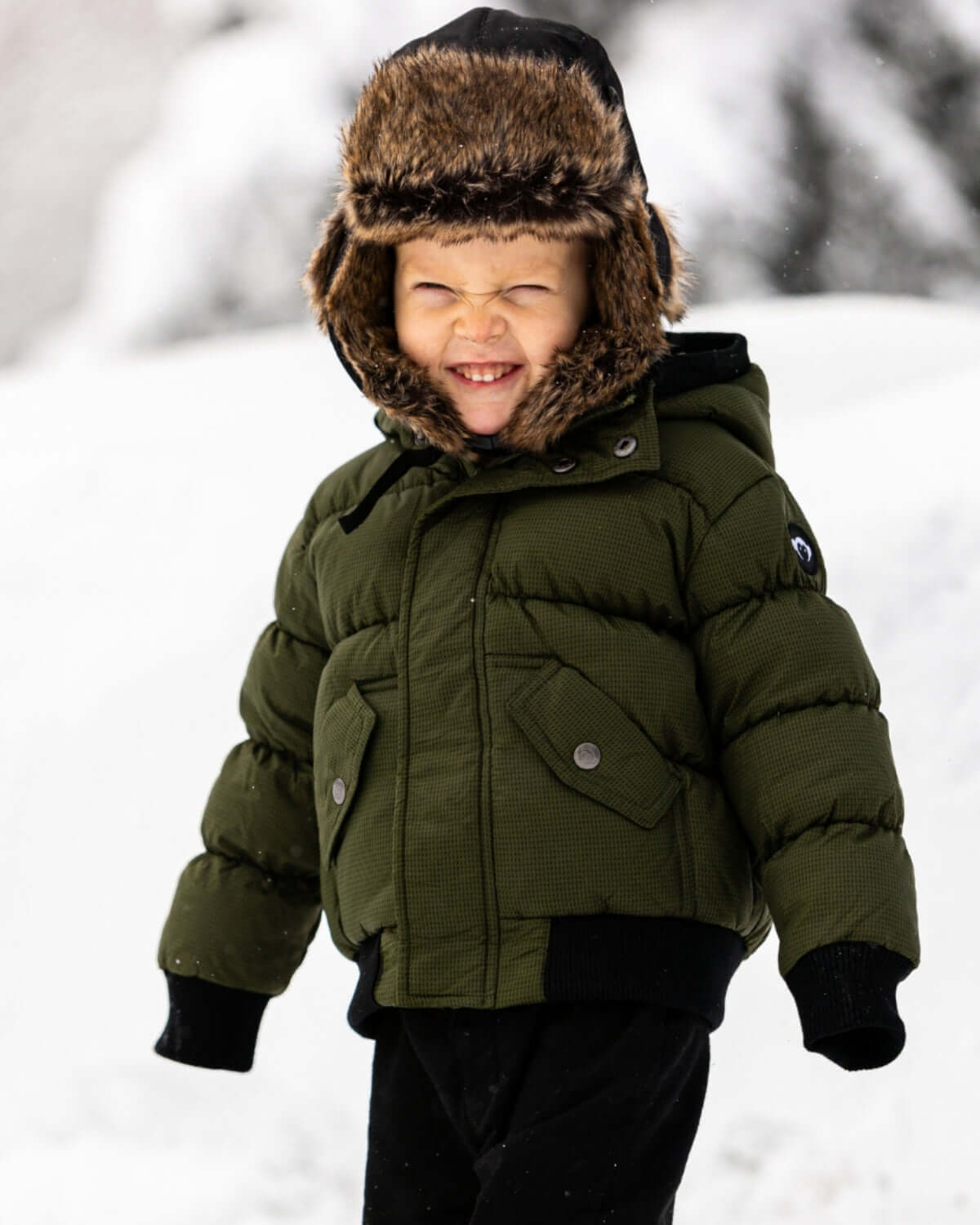 A joyful kid in a cozy puffy coat with faux fur hood, ready for winter fun in high-quality kids clothes.