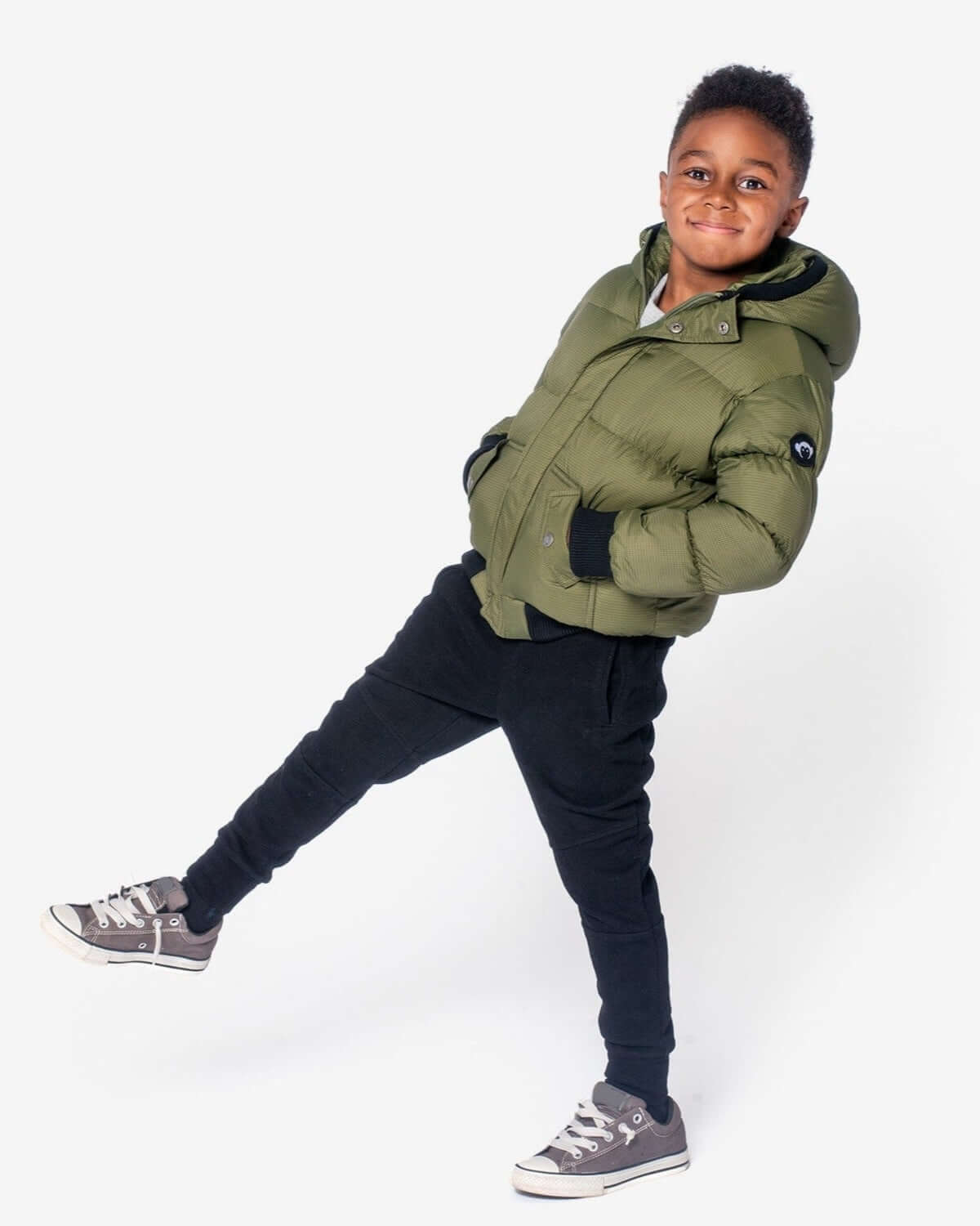 A confident boy in a stylish green Thunderstorm Puffy Coat, ready to conquer winter with playful flair. Perfect for kids' back-to-school!