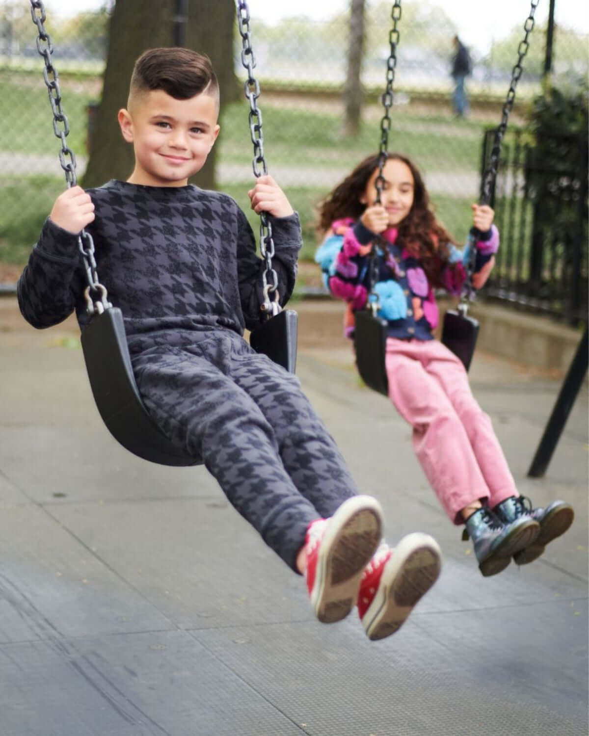 Kids in stylish black houndstooth Revel Crewnecks swinging joyfully, showcasing high-quality playful back-to-school vibes.