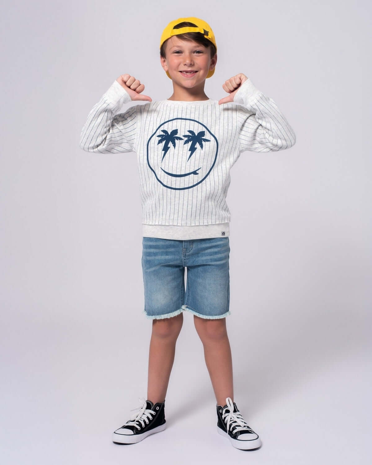 Joyful boy in striped Happy Surfing Highland Sweatshirt and shorts, ready for beach adventures! Fun kids clothes for stylish play.