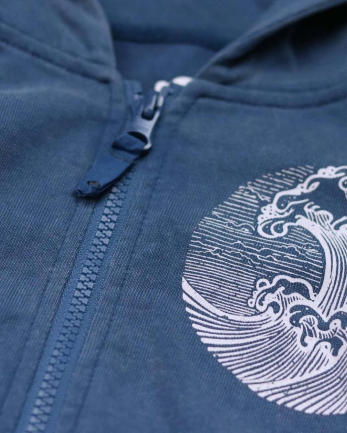 Close-up of a sunwashed blue hoodie with a stylish wave graphic, perfect for kids' school and play.