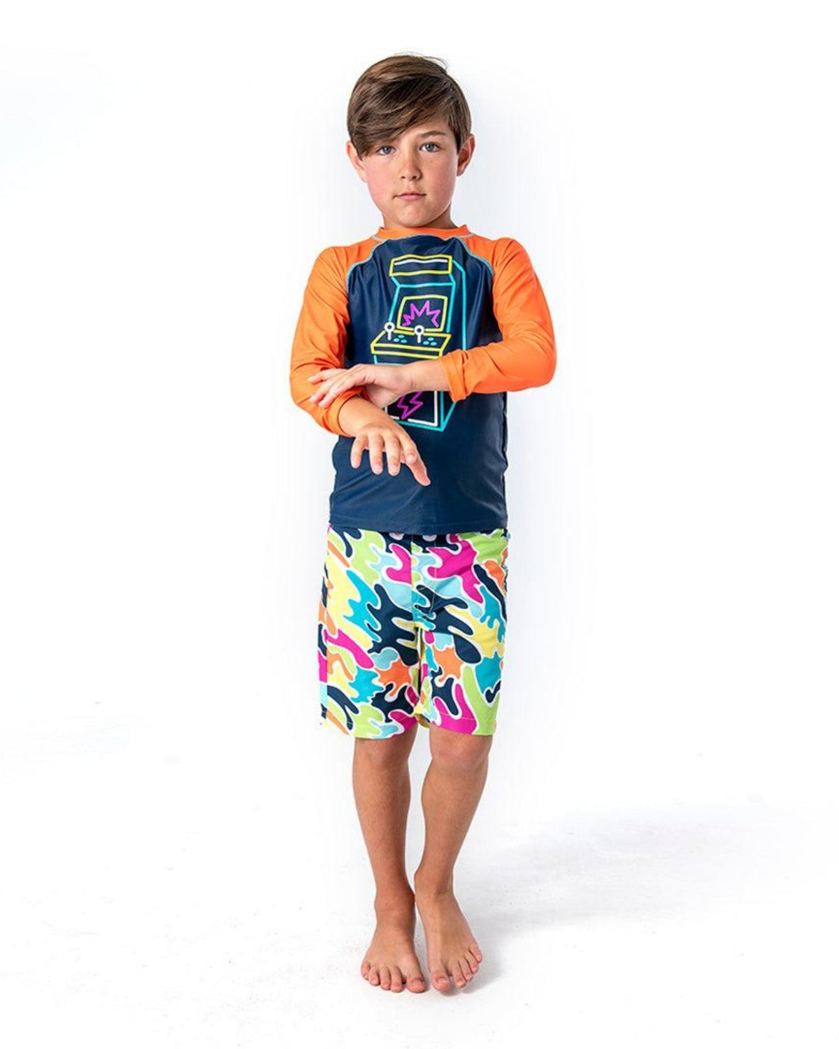 Stylish boy in vibrant Color Spill swim trunks, ready for beach adventures with UPF 50+ protection. Perfect for back to school fun!