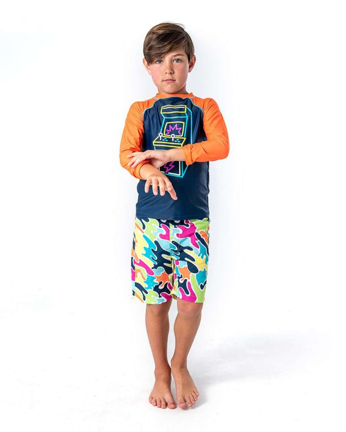 Color Spill Swim Trunks on a young boy with a vibrant camo pattern and UPF 50+ sun protection for beach fun.