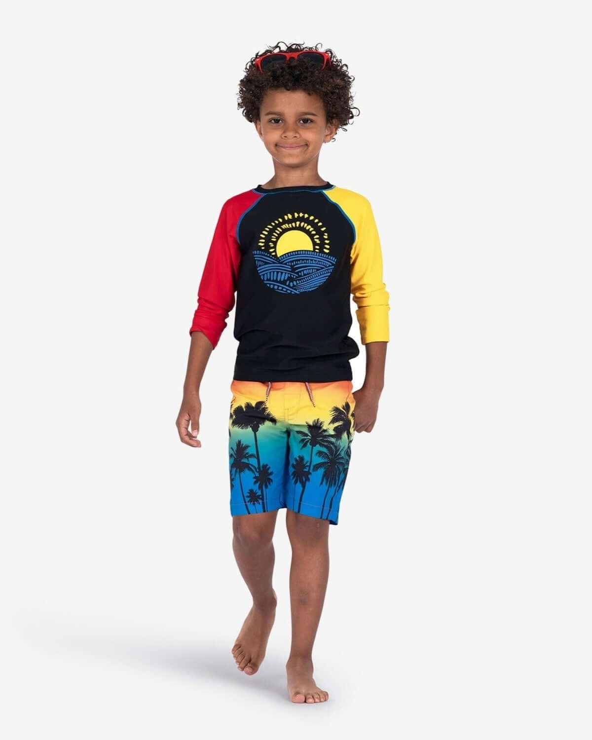 Stylish kid in colorful Ombre Palms Swim Trunks and sporty top, ready for sun and surf—perfect for back to school fun!