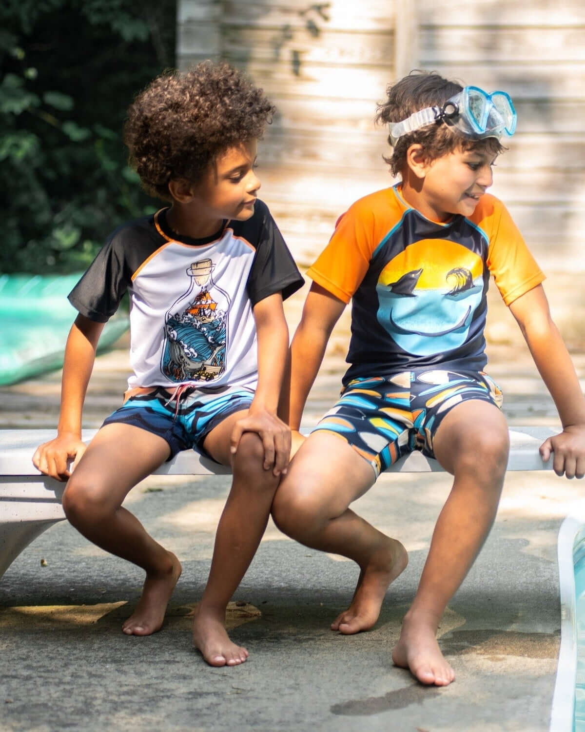 Two boys in stylish surf-themed swim trunks, ready for summer fun by the pool, showcasing high-quality kids clothes.