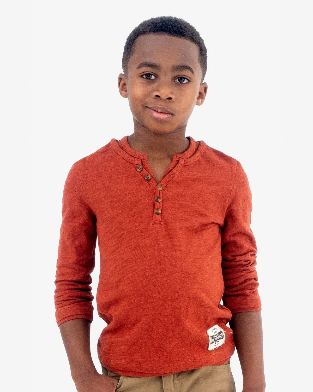A stylish boy in an Arabian Spice henley tee, showcasing fun kids clothes for a confident back-to-school look.