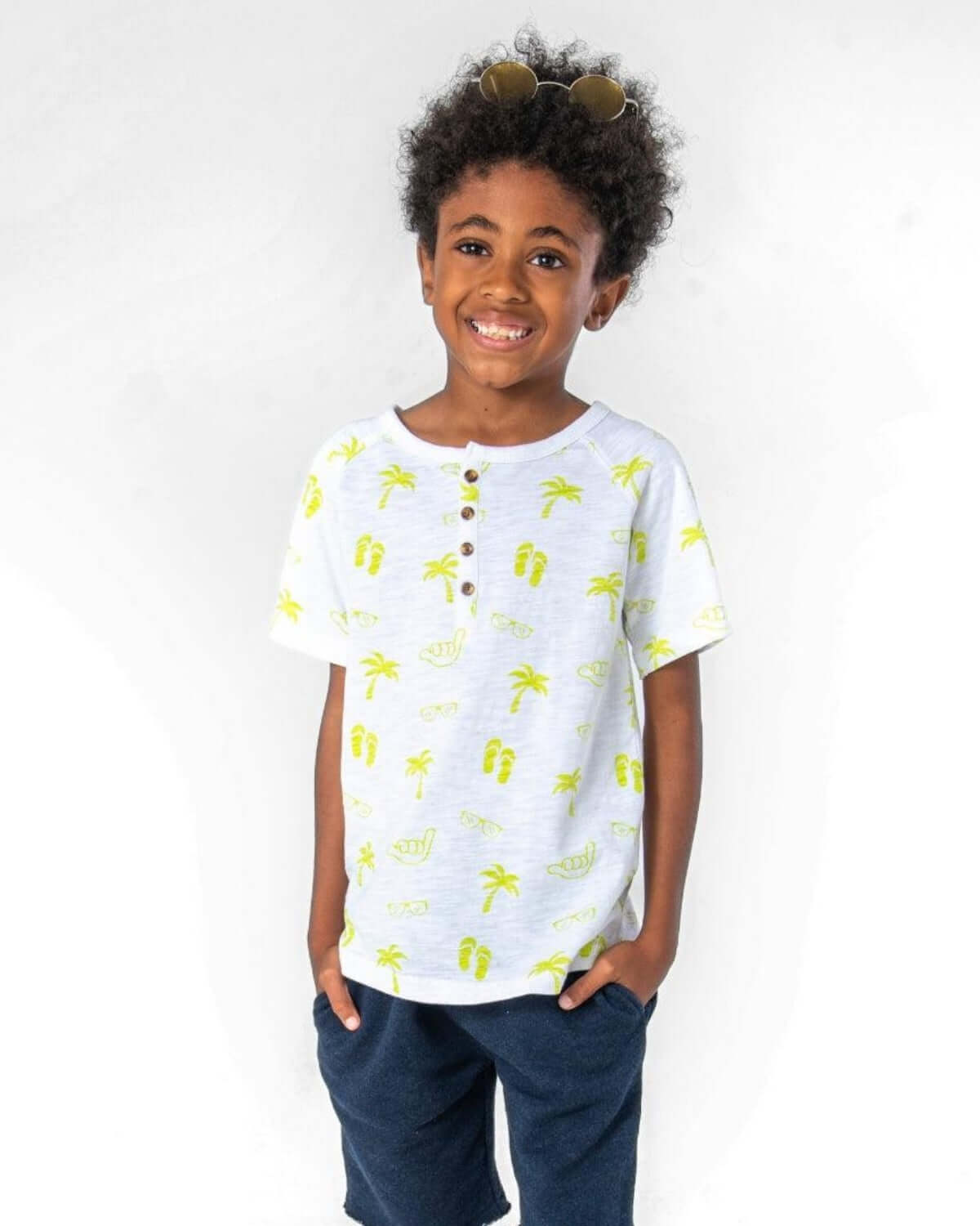 Young boy wearing Beach Vibes Clubhouse Henley tee with fun summer print and sunglasses, perfect for beach outings.