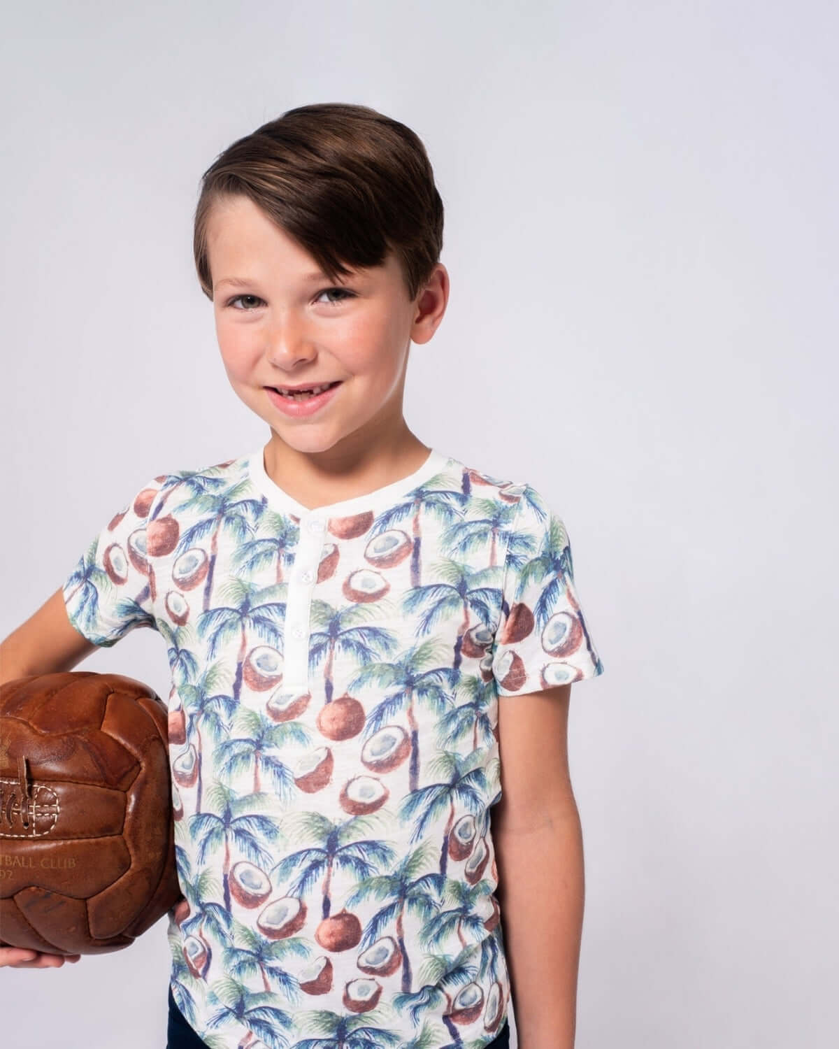 Happy kid in a coconut palms Henley shirt, ready for fun and style in high-quality boys clothes!