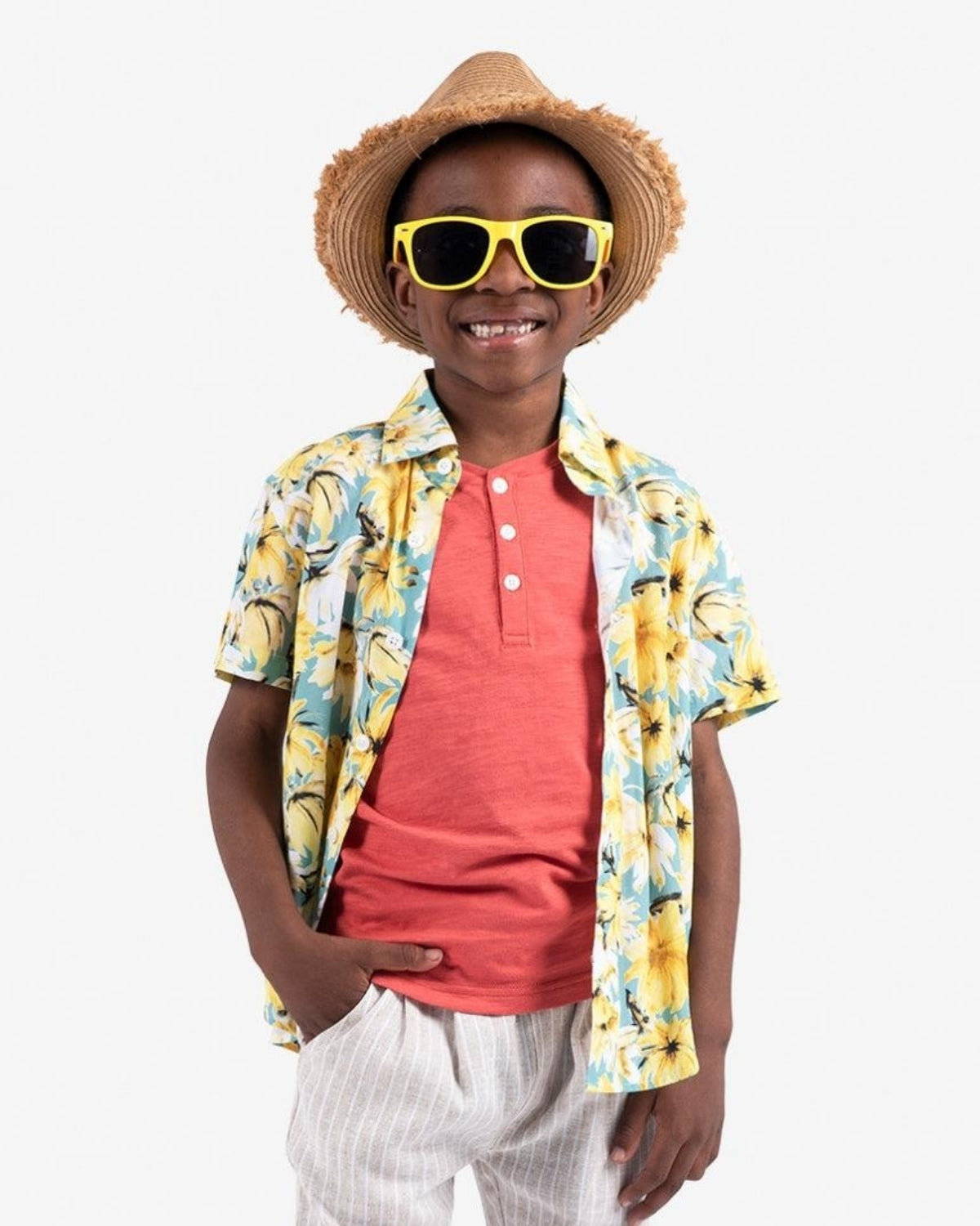 Stylish boy rocking a vibrant coral henley, floral shirt, and sunny shades, embracing summer fun in high-quality kids clothes.