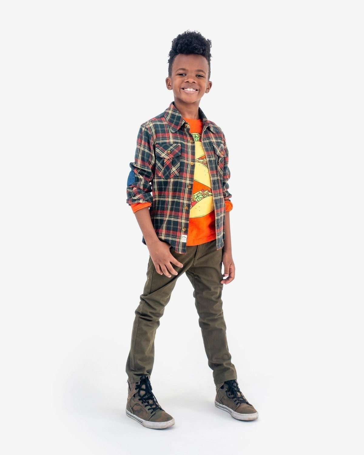 Stylish young boy in plaid flannel shirt, orange tee, and trendy pants—perfect for back to school adventures!