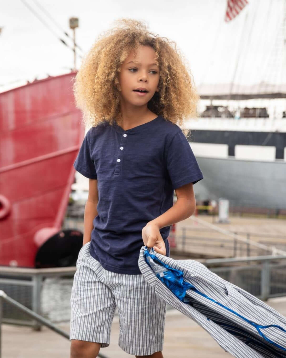 Navy Blue Day Party Henley worn by a child outdoors, paired with striped shorts, embodying comfort and style.