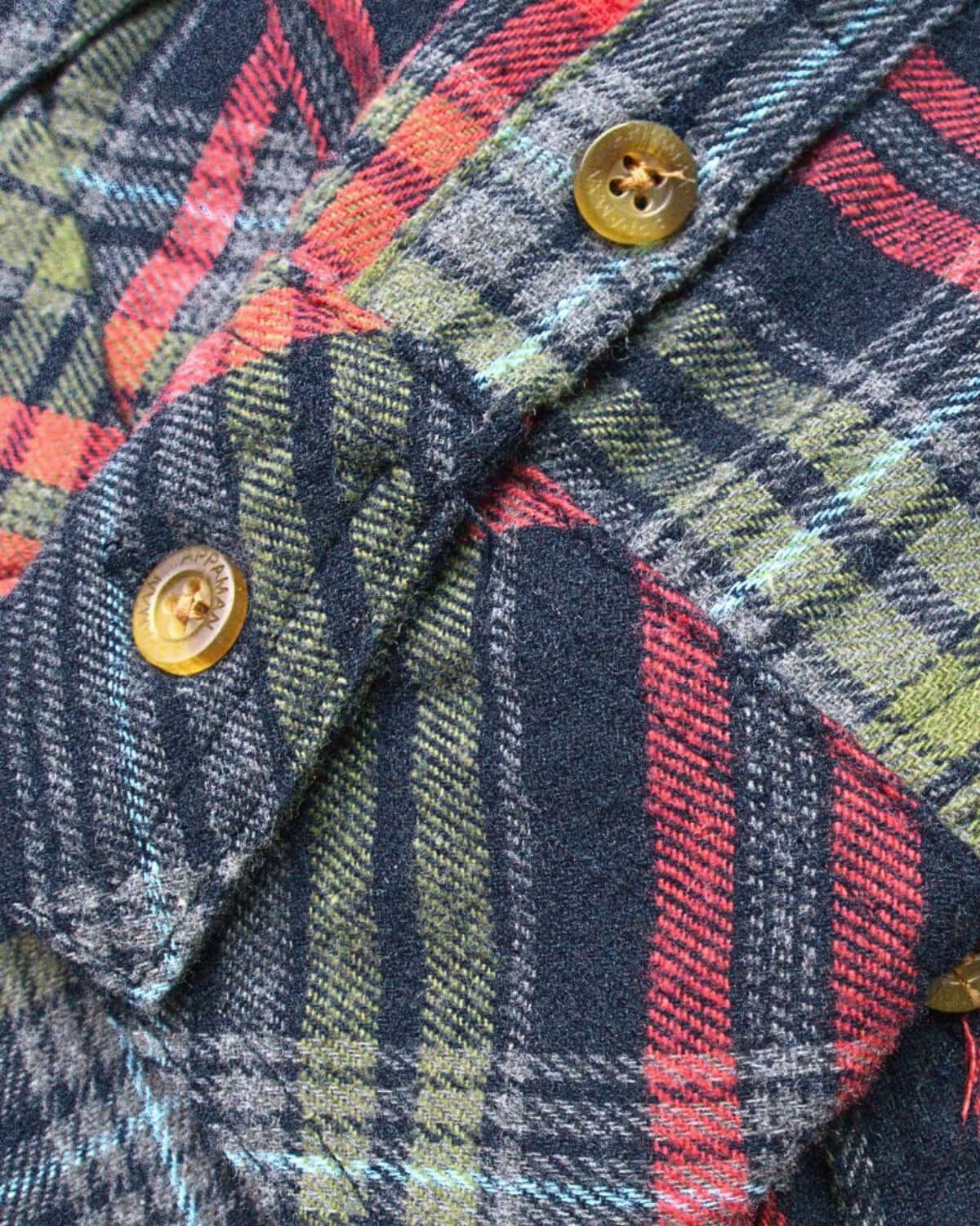 Navy and cranberry plaid flannel shirt detail highlighting soft cotton fabric and stylish buttons for kids' fashion.