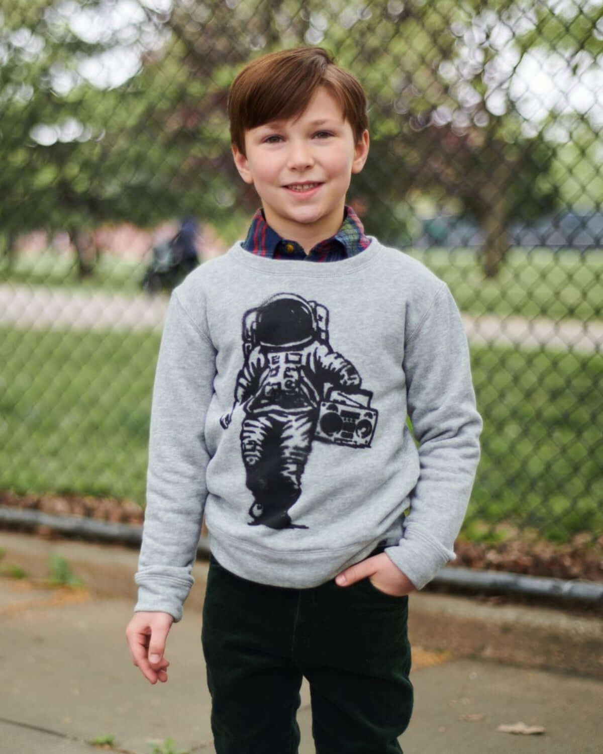 Stylish boy in a cozy astronaut sweatshirt, perfect for kids' back-to-school outfits. High-quality comfort meets playful style!