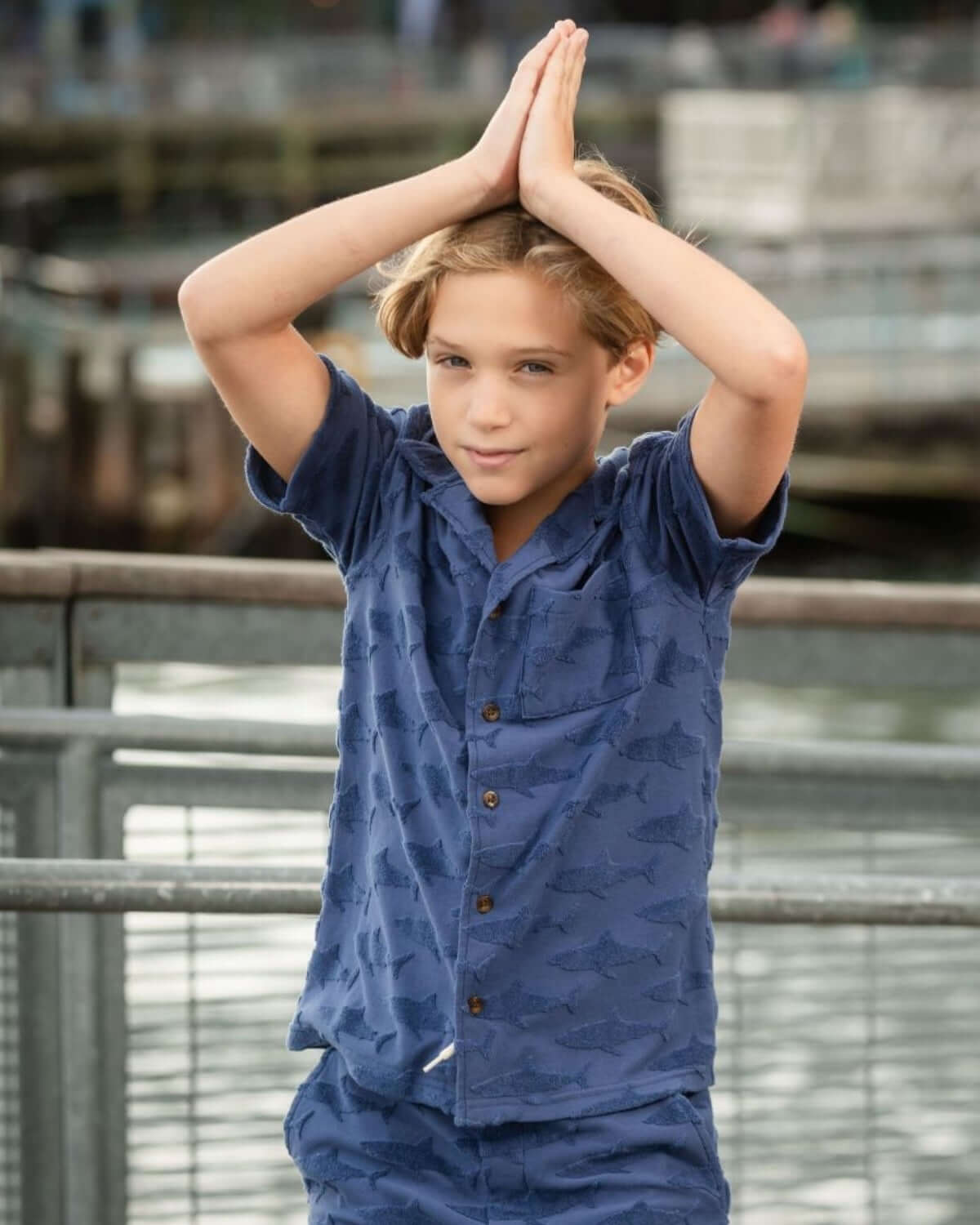Cool kid rocking a navy shark resort shirt, striking a fun pose by the water—perfect for beach days and adventures!
