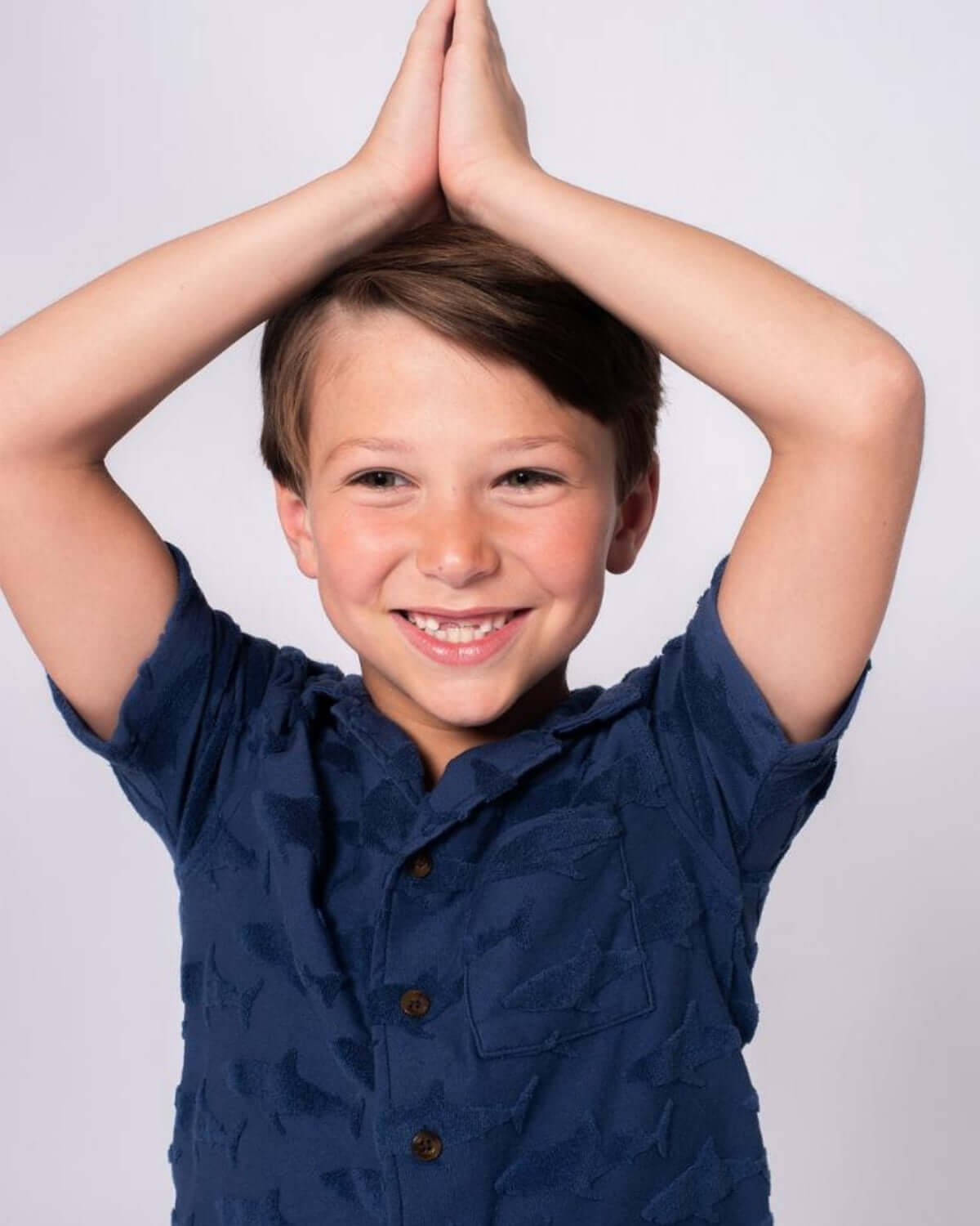 Boy wearing a Navy Shark Resort Terry Shirt, smiling with hands raised in a fun pose, showcasing a playful style.