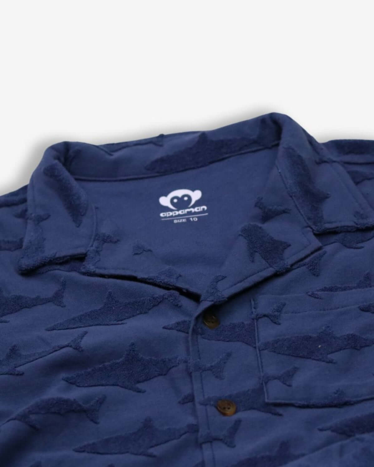 Navy resort shirt with playful shark print for boys, showcasing fun style and breathable fabric for summer adventures.