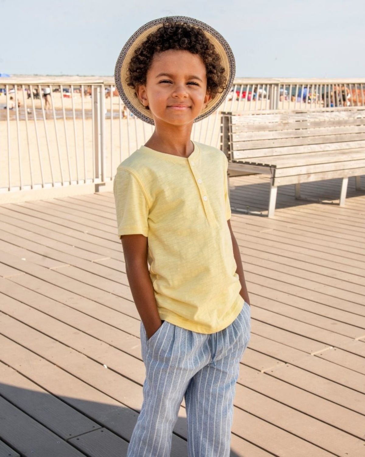Cheerful kid in a pale yellow henley, rocking playful style for summer fun—all about comfy kids clothes!