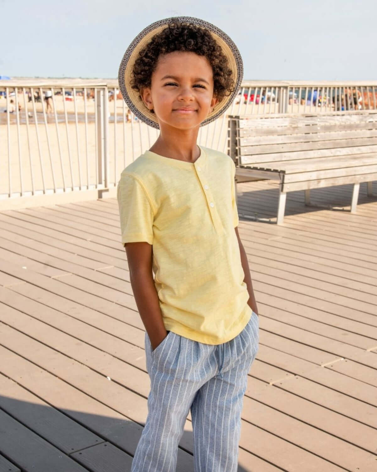 A child wearing a Pale Yellow Day Party Henley shirt on a sunny day at the beach.