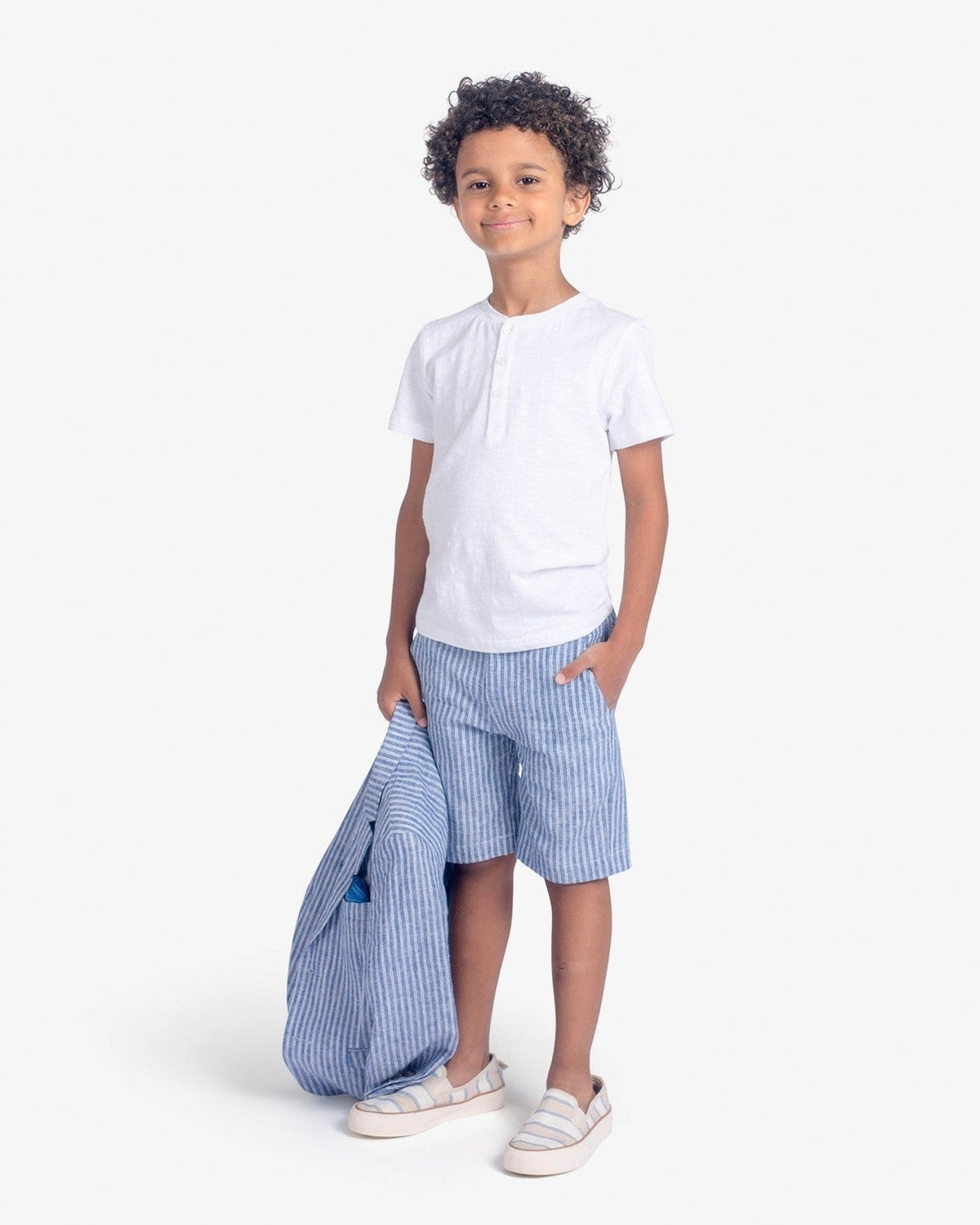 Stylish boy wearing a Pure White Day Party Henley and striped shorts, ready for a fun summer day in kids clothes.