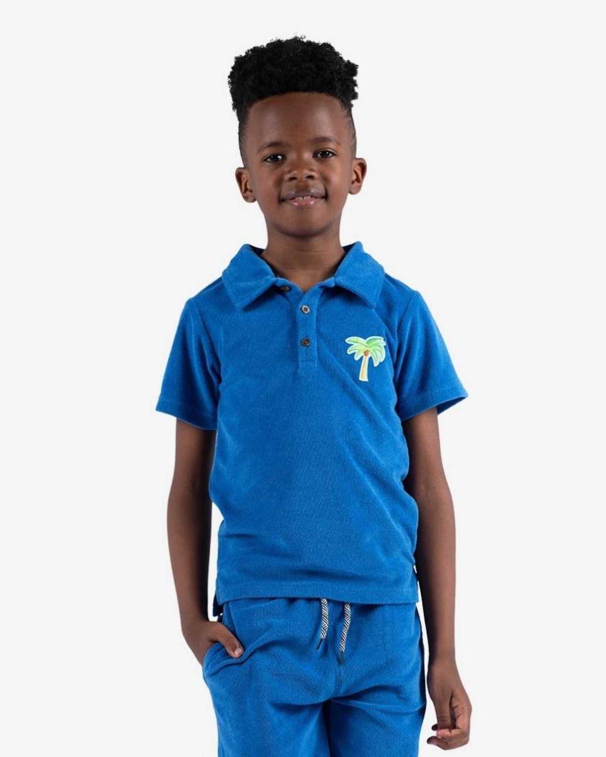 Fun-loving kid rocking the blue Surf the Web Fairbanks Polo with tropical palm embroidery, perfect for stylish back-to-school vibes.