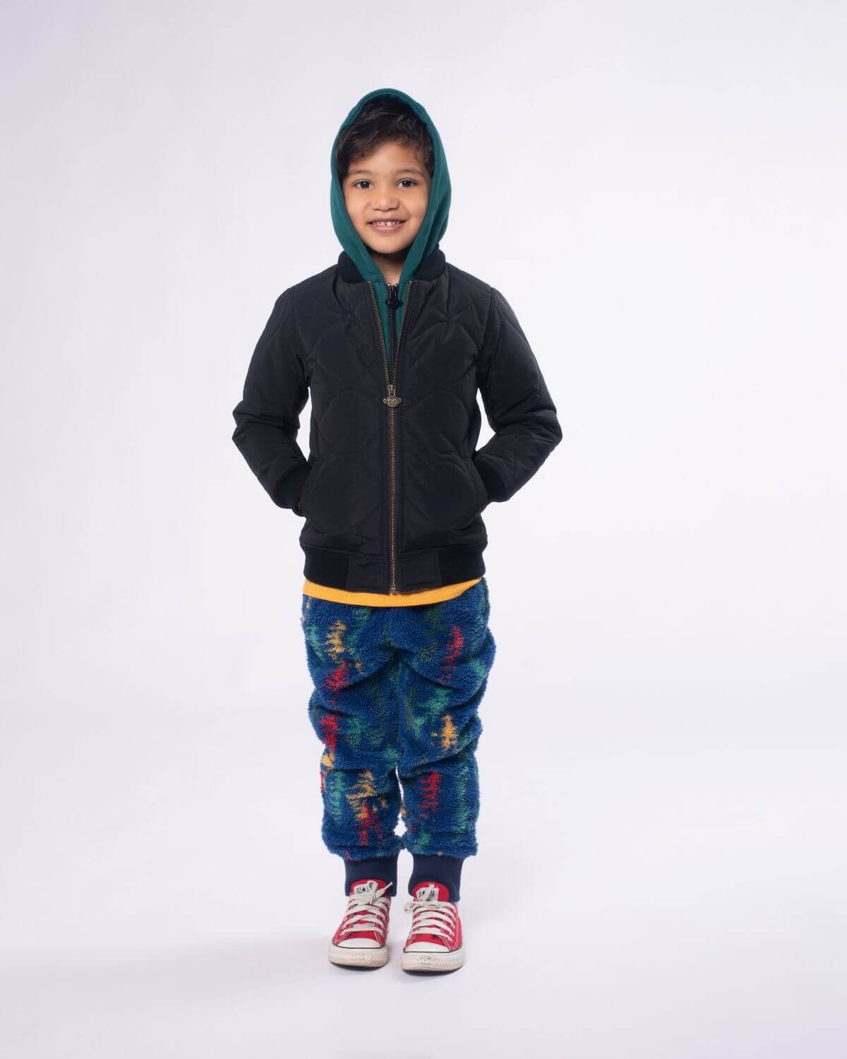 Stylish kid in a black BX Bomber jacket with a green hood, ready for adventure in vibrant, playful pants.
