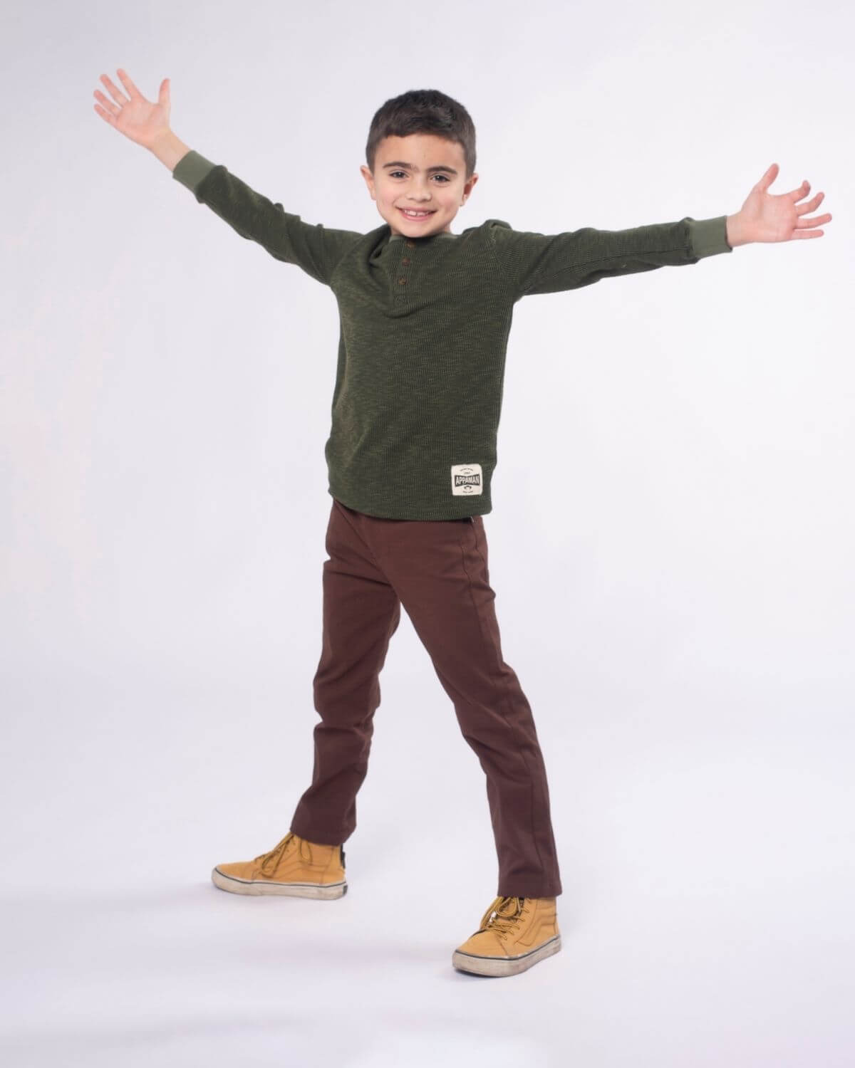 Stylish boy in dark olive thermal henley, spreading joy in high-quality kids clothes—perfect for back to school adventures!