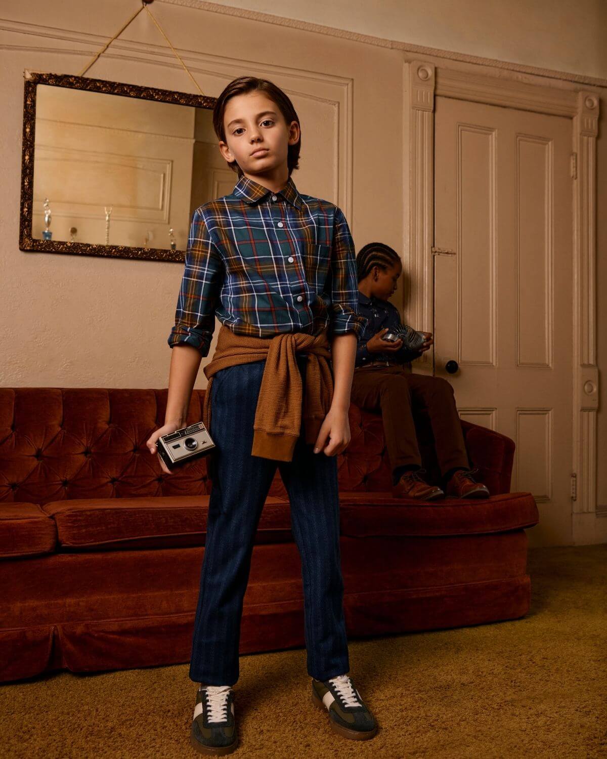 Stylish kid in plaid shirt and navy stripe pants, embodying modern boys clothes with playful confidence and charm.
