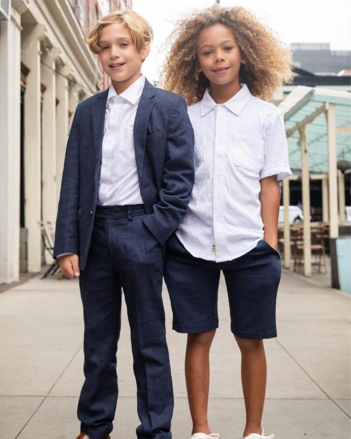 Stylish kids in modern outfits: one in a suit, the other in a comfy shirt and shorts, perfect for smart-casual adventures.