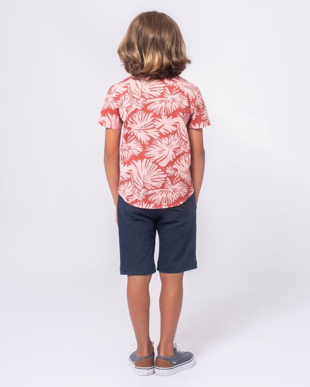 Trendsetting boy in a stylish coral floral shirt and navy blue shorts, ready for summer fun in high-quality kids clothes!