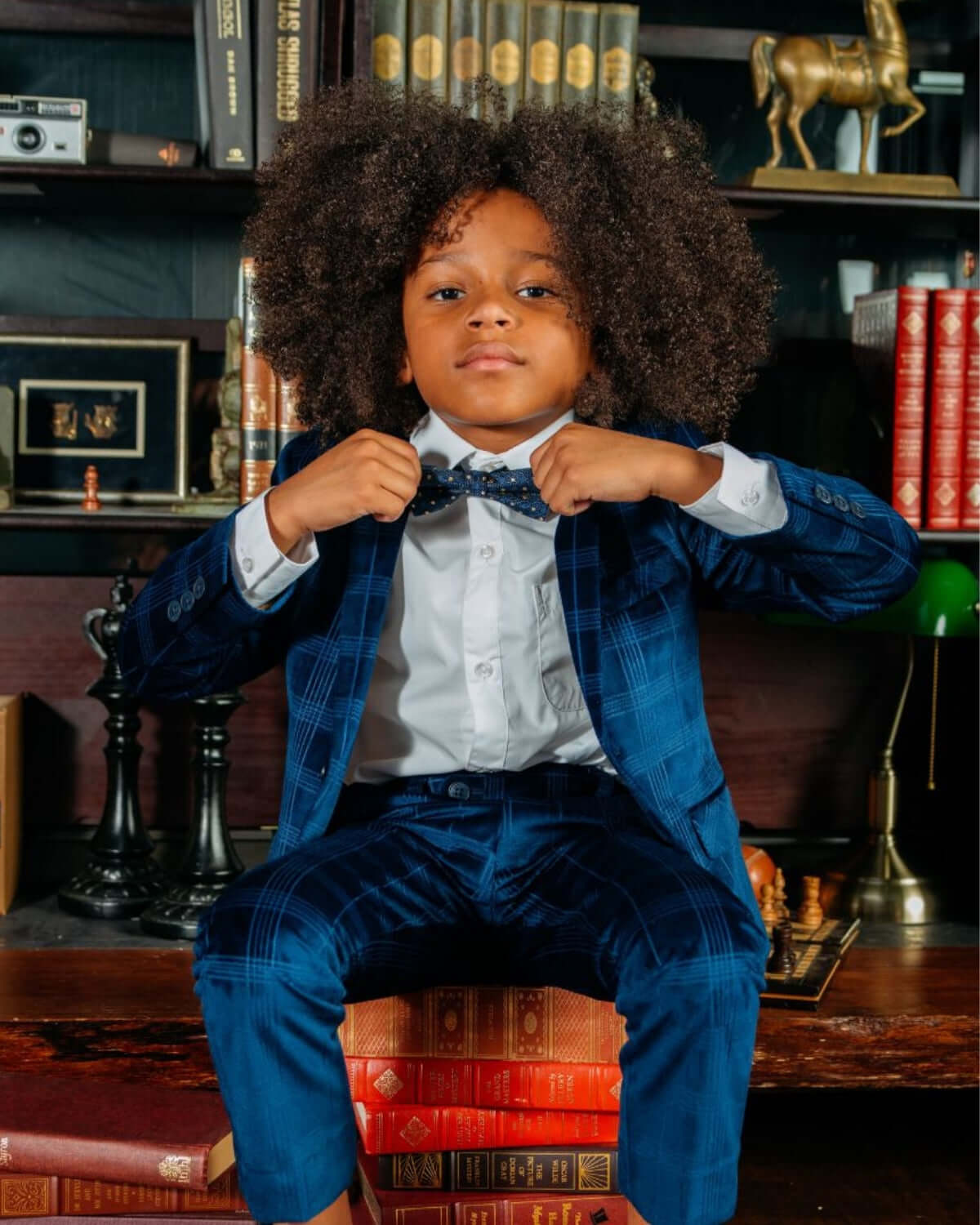 Dapper kid in blue velvet suit, adjusting bow tie, perfect for stylish school days or special occasions!