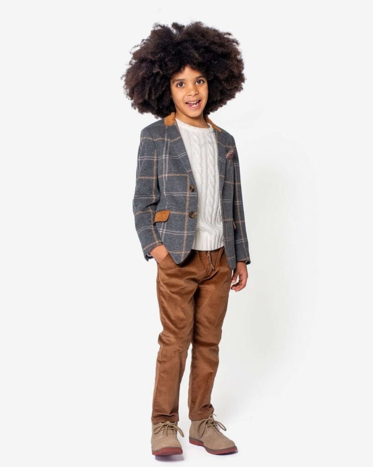 Stylish young boy in plaid blazer and cable-knit sweater, showcasing chic kids clothes for fun family gatherings.